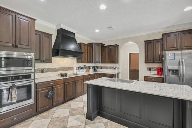 520 Young Rd, Waverly, TN 37185 - kitchen with arched walkways, a sink, custom range hood, an island with sink, and appliances with stainless steel finishes