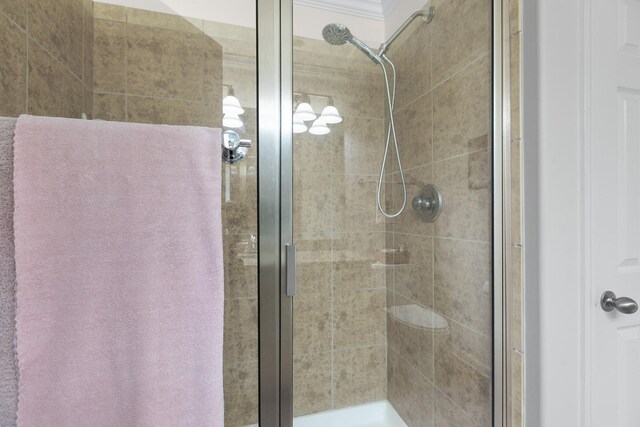 bathroom featuring crown molding and a stall shower