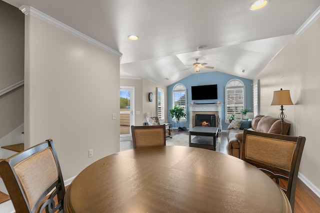 dining area featuring baseboards, vaulted ceiling, a lit fireplace, recessed lighting, and a ceiling fan