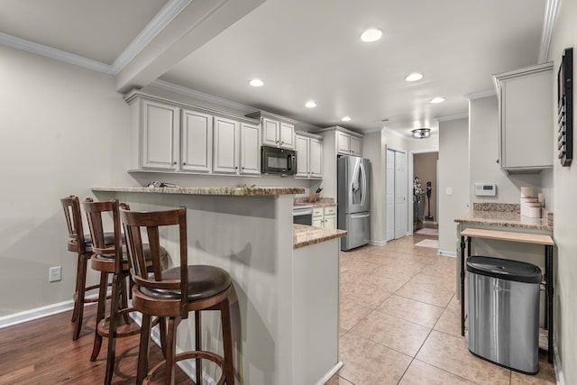 kitchen with stainless steel refrigerator with ice dispenser, ornamental molding, a kitchen bar, a peninsula, and black microwave