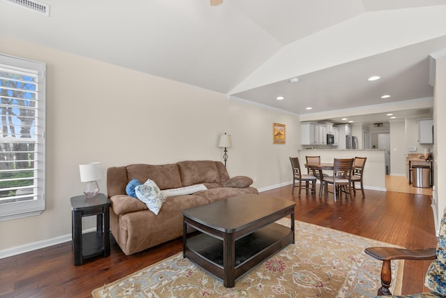 living room featuring hardwood / wood-style floors, baseboards, vaulted ceiling, and visible vents