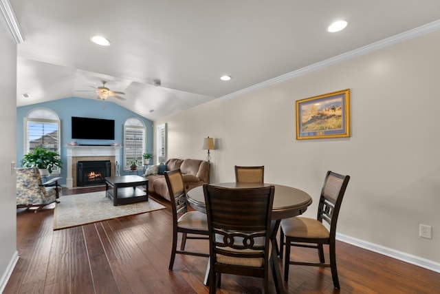 dining area with ceiling fan, plenty of natural light, a fireplace with flush hearth, and dark wood-style floors