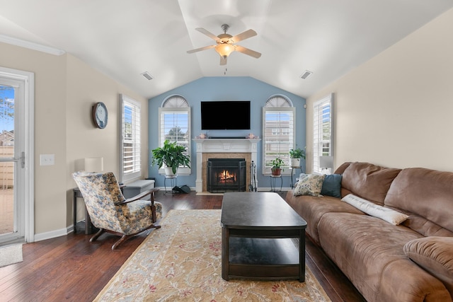 living room with dark wood-style flooring, visible vents, a ceiling fan, and a fireplace with flush hearth