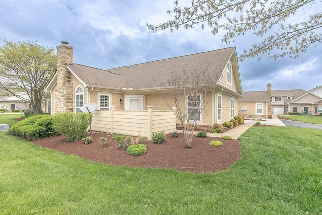 view of side of home with roof with shingles, a chimney, and a lawn
