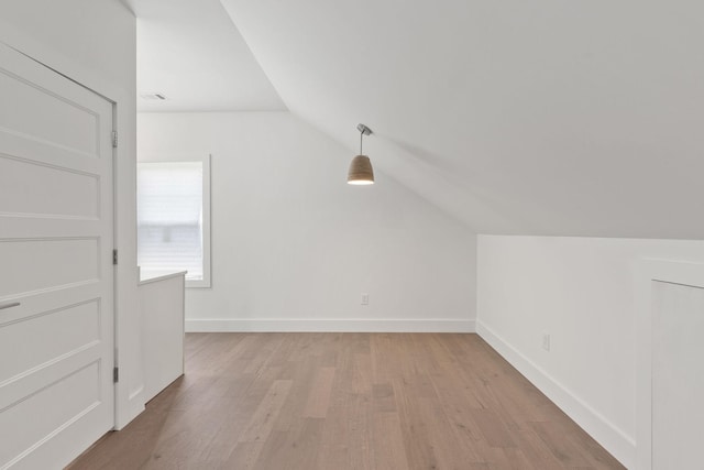 bonus room featuring light wood-style floors, baseboards, vaulted ceiling, and visible vents