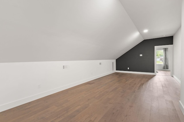 additional living space featuring visible vents, baseboards, wood finished floors, and lofted ceiling