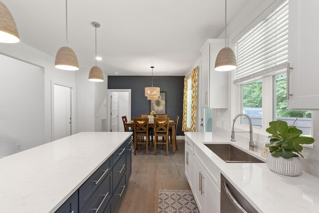 kitchen featuring white cabinets, wood finished floors, dishwasher, a sink, and decorative light fixtures