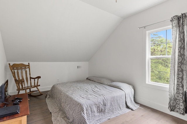 bedroom featuring wood finished floors, baseboards, multiple windows, and lofted ceiling