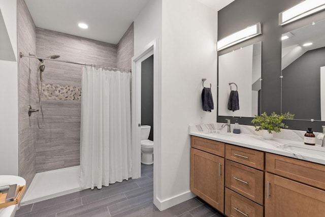 full bath featuring a sink, toilet, a tile shower, and double vanity