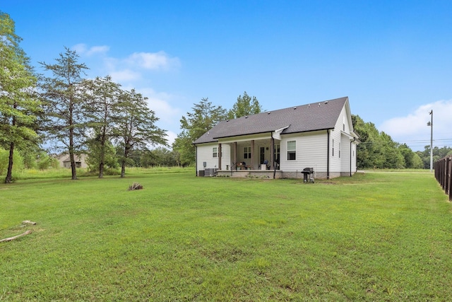 back of property featuring central AC, a shingled roof, a patio area, and a lawn