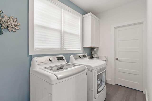 clothes washing area featuring dark wood finished floors, cabinet space, and washer and clothes dryer