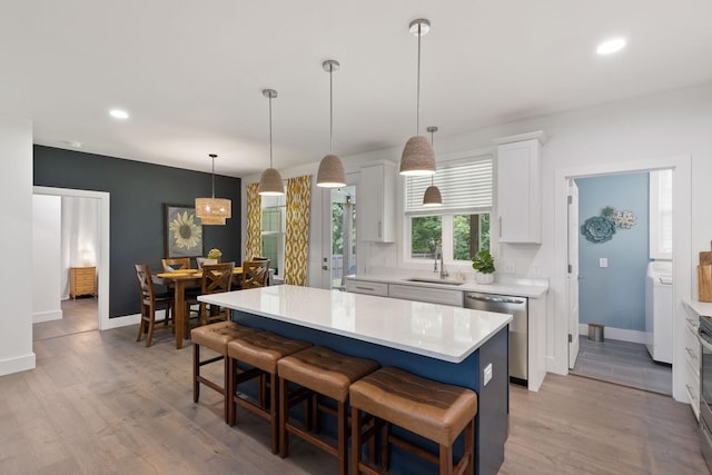kitchen with a breakfast bar, light countertops, a sink, stainless steel appliances, and baseboards