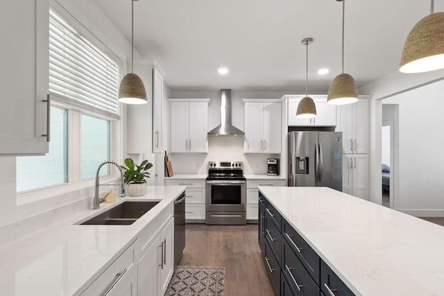 kitchen featuring wall chimney exhaust hood, white cabinets, recessed lighting, appliances with stainless steel finishes, and a sink
