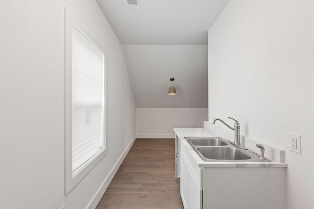 laundry area with wood finished floors, a sink, and baseboards