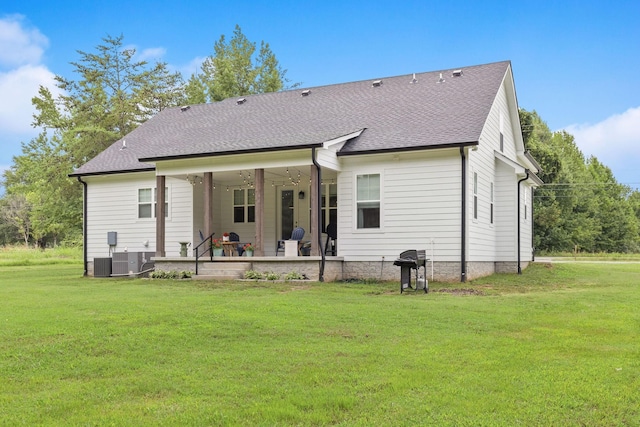 back of property featuring a yard, roof with shingles, a patio area, and central AC