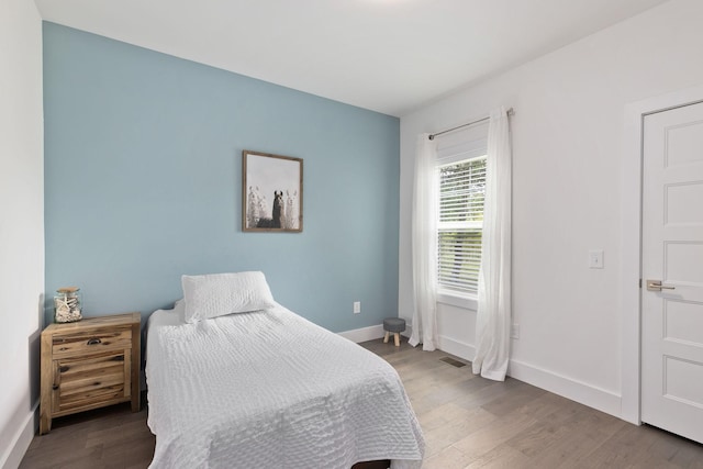 bedroom featuring visible vents, baseboards, and wood finished floors