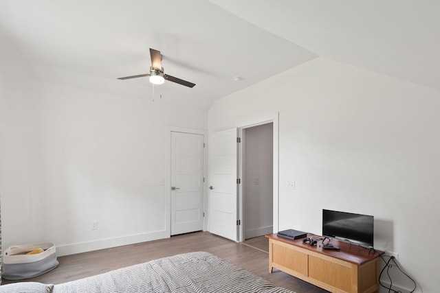 bedroom with baseboards, ceiling fan, wood finished floors, and lofted ceiling