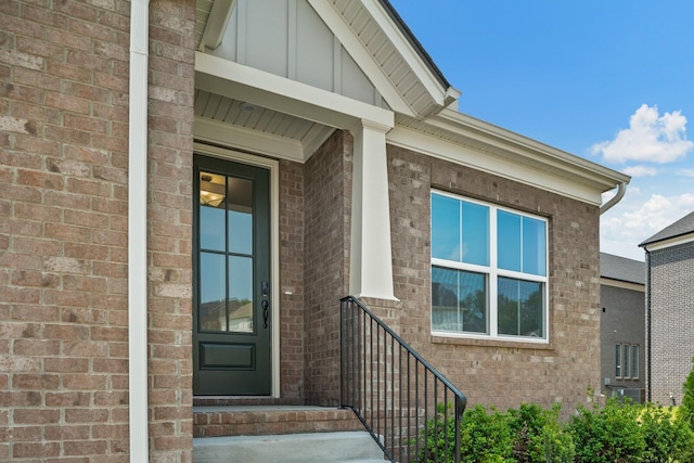 doorway to property with board and batten siding and brick siding