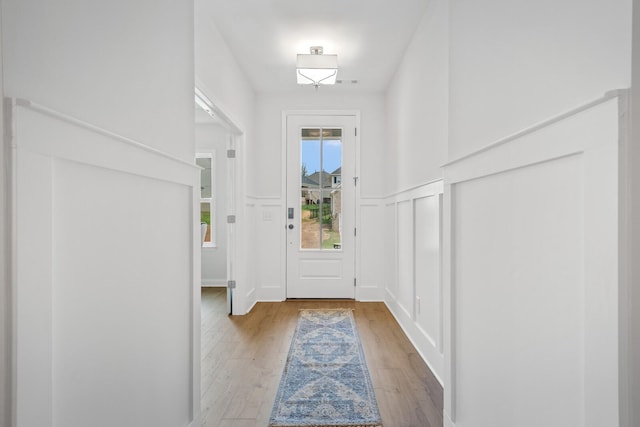 interior space with wainscoting, a decorative wall, and light wood finished floors