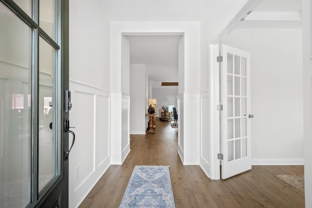foyer with wainscoting, wood finished floors, and a decorative wall