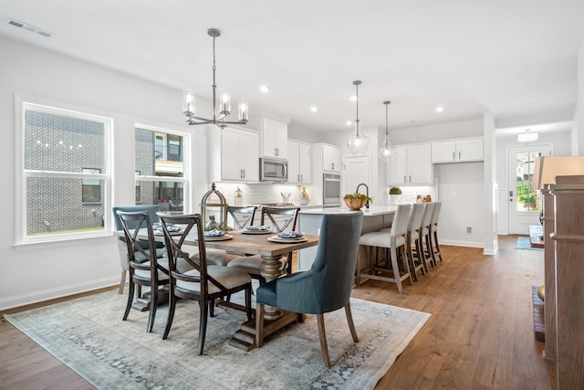 dining space with light wood-type flooring, baseboards, a notable chandelier, visible vents, and recessed lighting