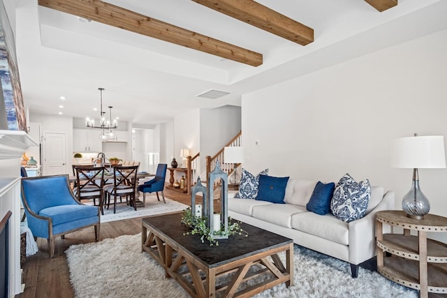 living area featuring an inviting chandelier, recessed lighting, beamed ceiling, stairway, and wood-type flooring