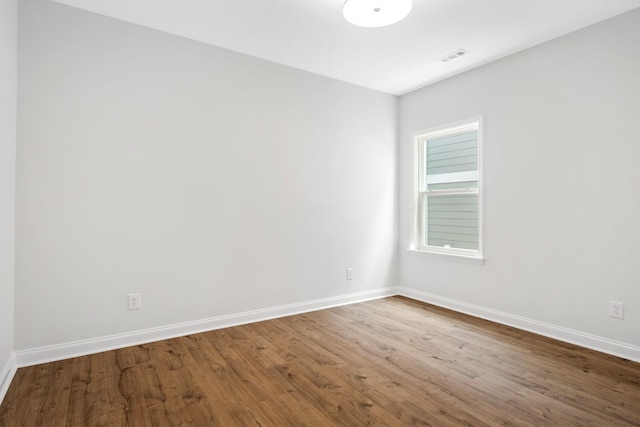 spare room with baseboards, wood finished floors, and visible vents