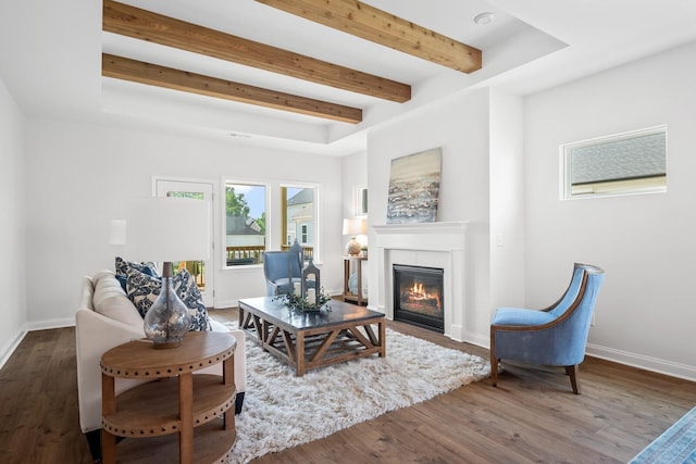 living room featuring wood finished floors, baseboards, a glass covered fireplace, and beam ceiling
