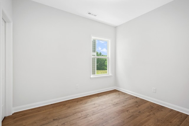 empty room with baseboards, wood finished floors, and visible vents