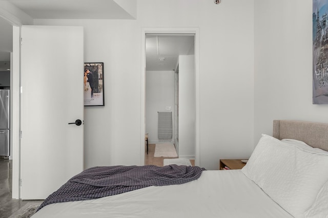 bedroom featuring freestanding refrigerator, ensuite bath, wood finished floors, attic access, and baseboards