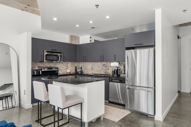 kitchen with visible vents, a sink, dark countertops, stainless steel appliances, and decorative backsplash