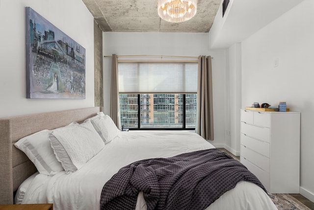 bedroom with baseboards, an inviting chandelier, and wood finished floors