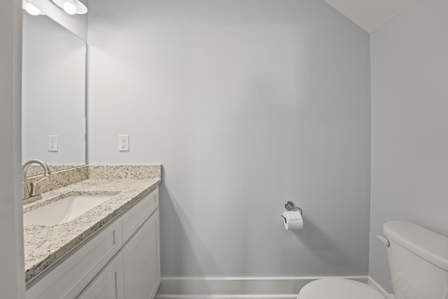 bathroom featuring toilet, vanity, and baseboards