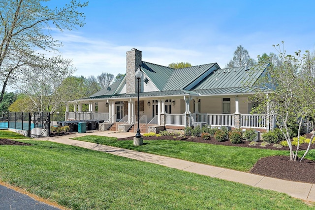 view of front of house with a chimney, a front lawn, a porch, a standing seam roof, and metal roof