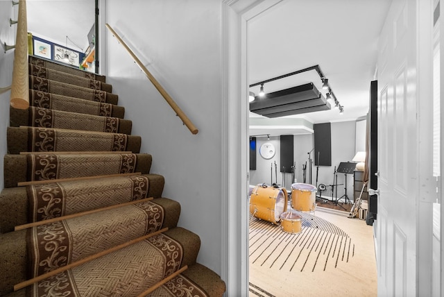 staircase featuring carpet floors and rail lighting