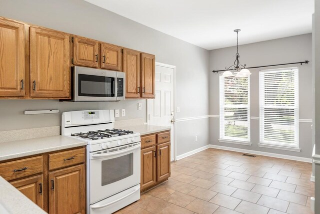 kitchen featuring light countertops, white range with gas stovetop, and stainless steel microwave