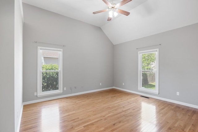 empty room with vaulted ceiling, visible vents, a ceiling fan, light wood-type flooring, and baseboards