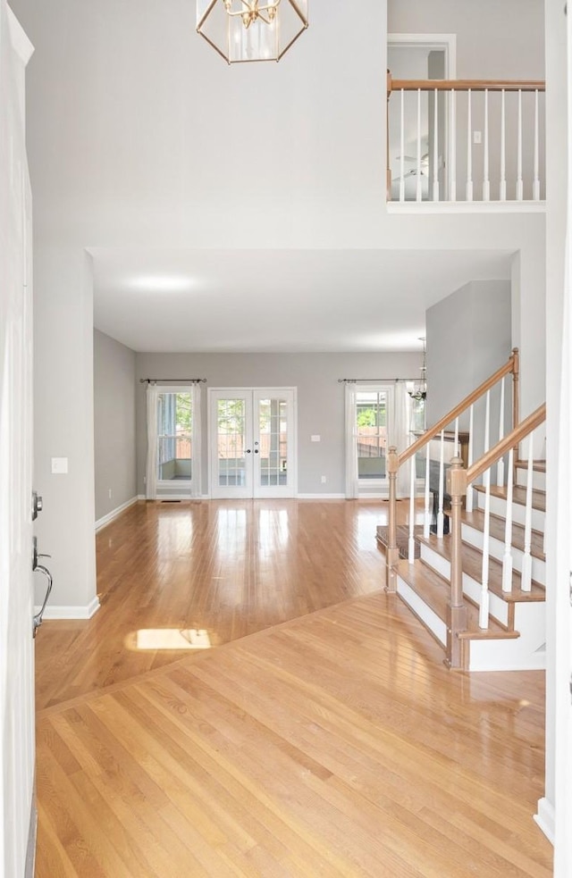 foyer entrance featuring french doors, wood finished floors, a chandelier, and stairway