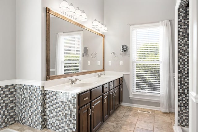 full bathroom with a sink, double vanity, and plenty of natural light