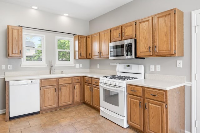 kitchen with a sink, white appliances, light tile patterned floors, light countertops, and recessed lighting