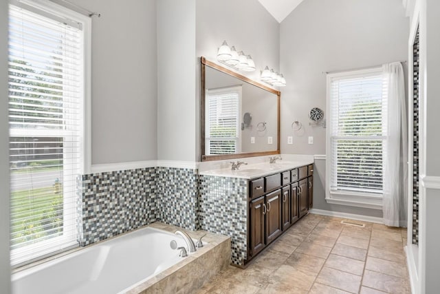 bathroom with a garden tub, a sink, and plenty of natural light