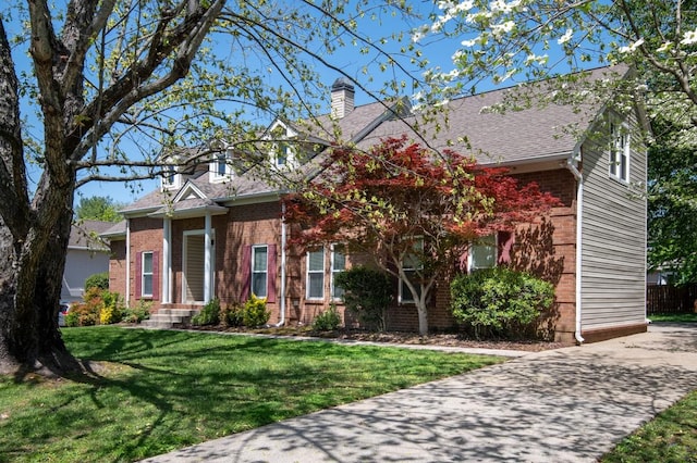 view of front of house with brick siding, roof with shingles, a chimney, and a front lawn