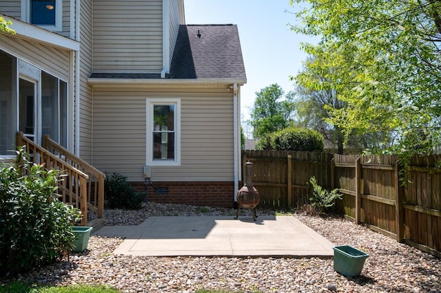 exterior space featuring crawl space, a shingled roof, fence, a patio, and a sunroom
