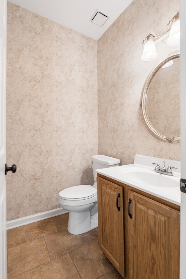 half bathroom featuring toilet, baseboards, visible vents, stone finish flooring, and vanity