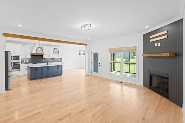 6913 Pembrooke Farms Dr, Murfreesboro, TN 37129 - unfurnished living room with a fireplace, light wood-style floors, recessed lighting, and a sink