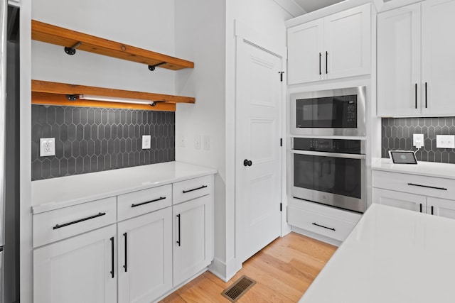 6913 Pembrooke Farms Dr, Murfreesboro, TN 37129 - kitchen featuring built in microwave, light countertops, stainless steel oven, light wood-style flooring, and backsplash