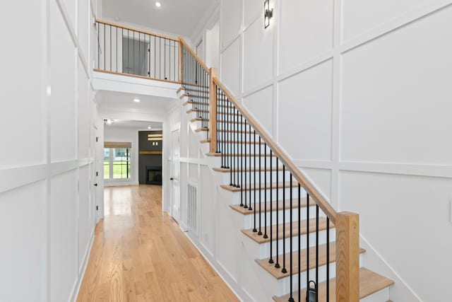 6913 Pembrooke Farms Dr, Murfreesboro, TN 37129 - staircase with a fireplace, wood finished floors, a decorative wall, and recessed lighting