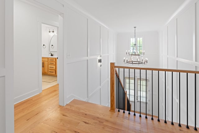 6913 Pembrooke Farms Dr, Murfreesboro, TN 37129 - hallway featuring an upstairs landing, a sink, an inviting chandelier, light wood finished floors, and baseboards