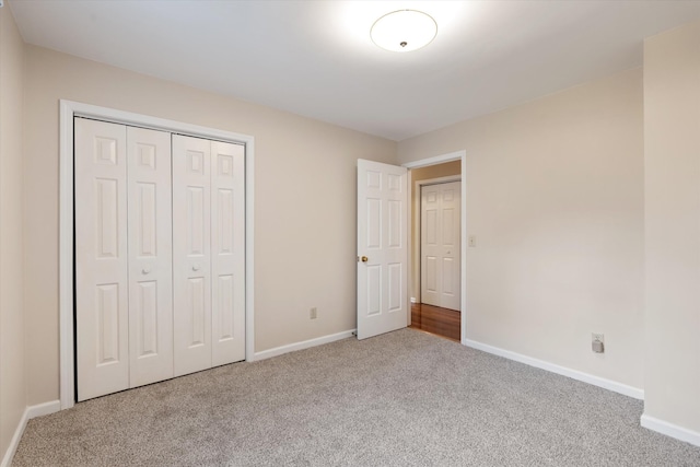 unfurnished bedroom with a closet, carpet flooring, and baseboards