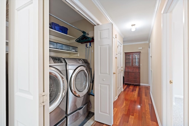laundry area with laundry area, ornamental molding, wood finished floors, baseboards, and washer and clothes dryer